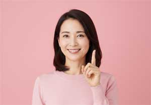 明るい笑顔でポイントを指し示す女性。夫婦の会話に悩み「本音が言えない」と一人で抱え込む40代女性へ、心の距離を縮めるための解決策やヒントを前向きに提示し、一歩踏み出す勇気を与えるシチュエーション。